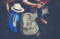Close up of Young hipster traveller man siting on bench with backpack in train station waiting for go travel with the train. Travel concept.